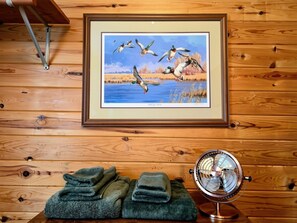 A framed wildlife painting, a fan, and folded towels on a wooden surface.