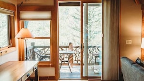 A room with a wooden table, a sofa, a sliding glass door leading to an outdoor deck with chairs and a table. - Close to Keystone - Hot Tubs & Private Deck! (Keystone)