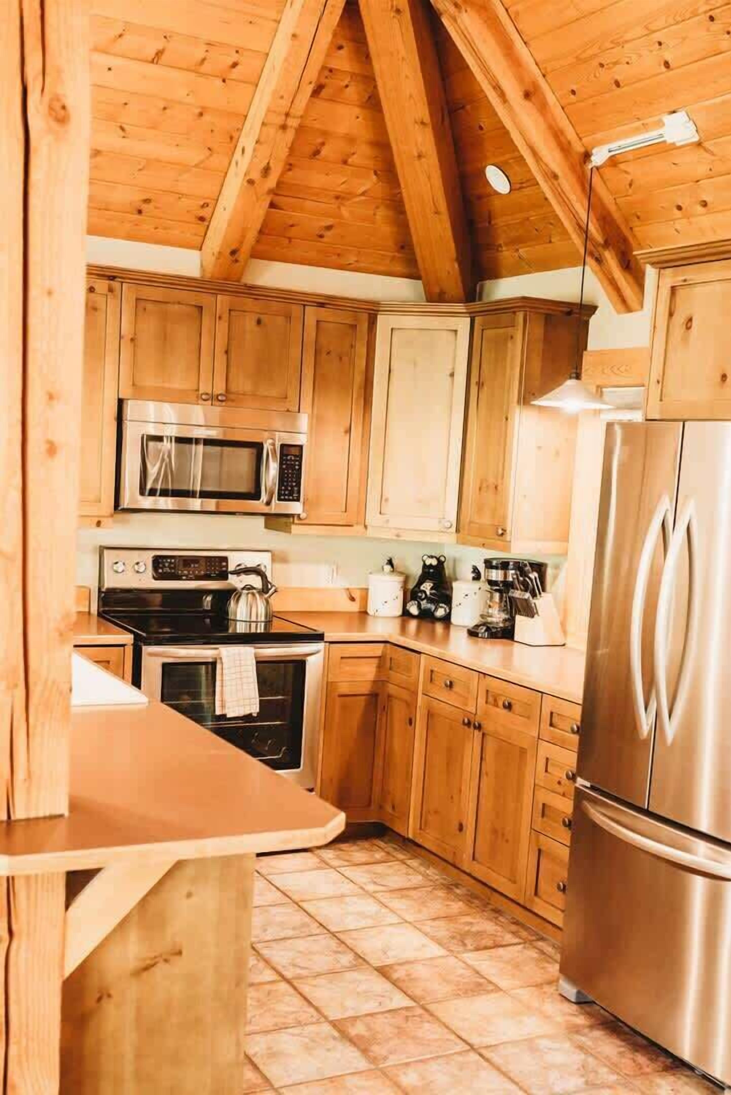 A kitchen with wooden cabinets, a microwave, stove, and refrigerator.
