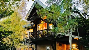 A two-story building with a balcony, a stone pathway, and a signpost with directional arrows. - Close to Keystone - Hot Tubs & Private Deck! (Keystone)