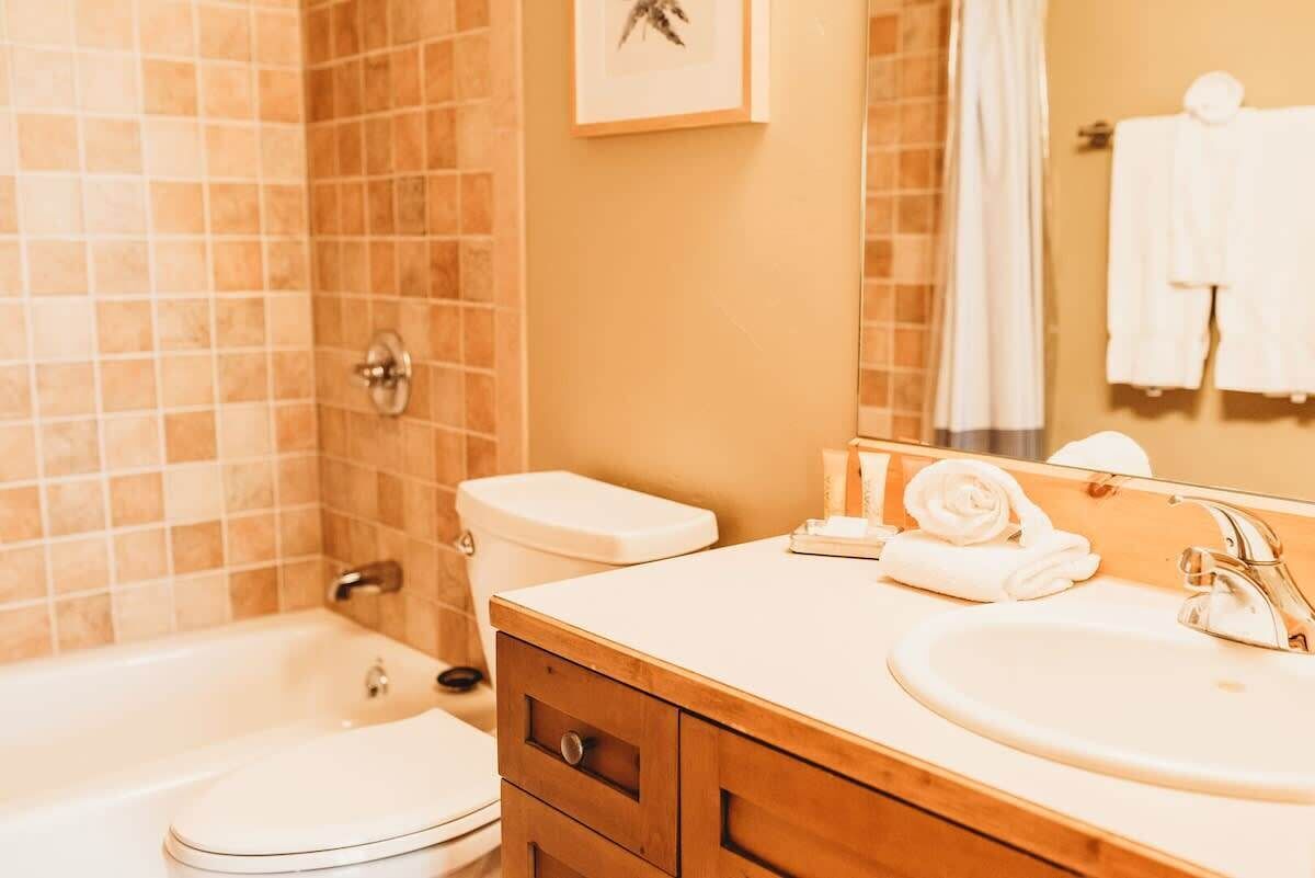 Een badkamer met een badkuip, toilet, wastafel en een spiegel.