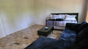 A room with a black sofa, a bed with striped bedding, and a small black table. - Stay at Lazy Lure just minutes to several surrounding lakes (Quitman)