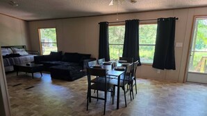 A spacious living area with a dining table, black sofa, and a ceiling fan. - Stay at Lazy Lure just minutes to several surrounding lakes (Quitman)