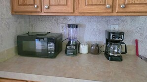 A kitchen with wooden cabinets, a microwave, a blender, and a coffee maker. - Stay at Lazy Lure just minutes to several surrounding lakes (Quitman)