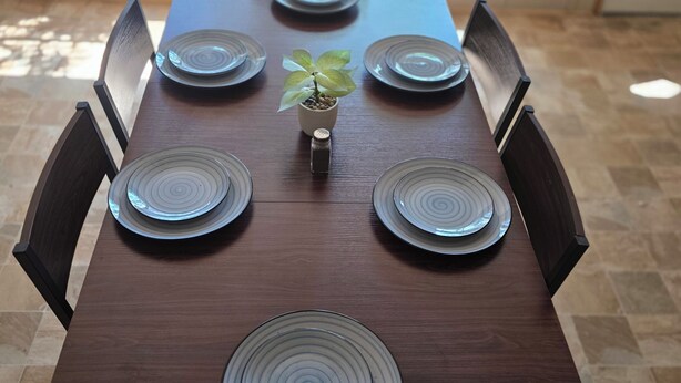 A dining table with six plates, a small plant, and chairs. - Stay at Lazy Lure just minutes to several surrounding lakes (Quitman)