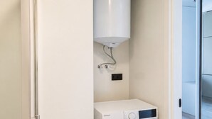 Uma lavanderia compacta com máquina de lavar de abertura frontal e aquecedor de água.