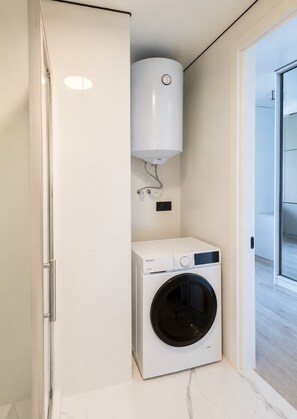 Ein kleiner Hauswirtschaftsraum mit einer Waschmaschine mit Frontlader und einem Durchlauferhitzer.