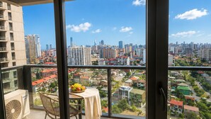Varanda com mesa e cadeiras, um ventilador e vista para a cidade.