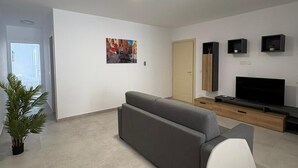 Una sala moderna con un sofá, un televisor y una planta pequeña.