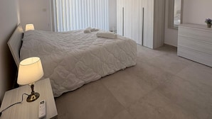 Un dormitorio moderno con cama, lámpara de noche, armario y espejo.