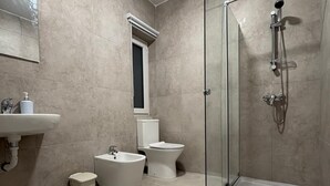 Un baño moderno con ducha de vidrio, bañera independiente, inodoro y lavamanos.