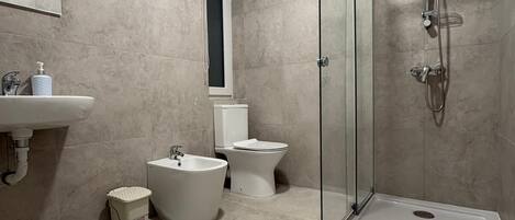 Un baño moderno con ducha de vidrio, bañera independiente, inodoro y lavamanos.