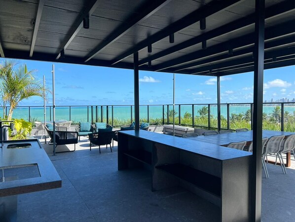 Ein überdachter Außenbereich mit langem Tisch und Stühlen, mit Blick auf eine schöne Aussicht.