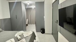 Et moderne hotelværelse med seng, fjernsyn og et badeværelse, der kan ses gennem en dør.