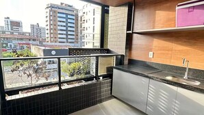 Et moderne køkken med balkon, fliserede vægge og udsigt over bybilledet.