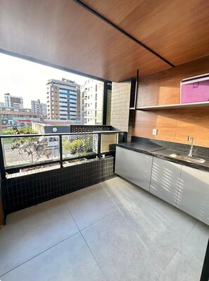 Eine moderne Küche mit Balkon, geflieste Wände und Blick auf die Stadt.