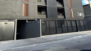En moderne bygning med en grå facade, flere balkoner og et synligt skilt med 'JAR' og 'Son'.