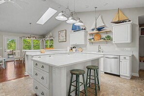 A kitchen with a large island, pendant lights, a sailboat decoration, and a view of the outdoors. - Beaver Lake Access Retreat w Deck & Grill! (Garfield)