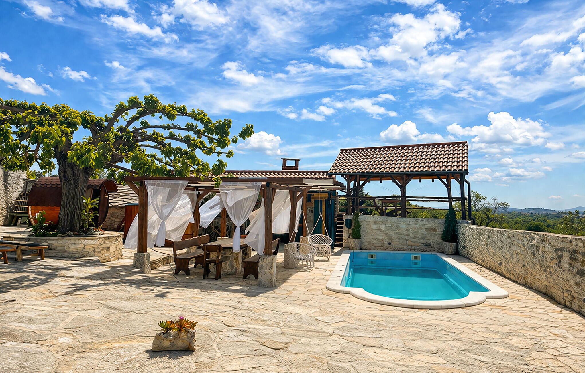 A pool area with a pergola, outdoor seating, and a view of the landscape.