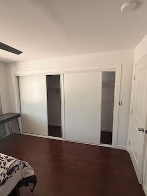Ein Zimmer mit Schiebetüren zum Kleiderschrank, einem Bett und einem Deckenventilator.