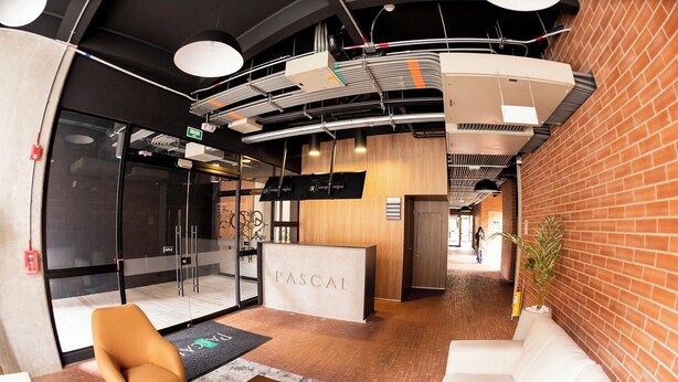 A reception area with a reception desk, a seating area with a sofa and chairs, and a brick wall. - Corazón fotográfico  (Bogotá)