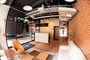 A reception area with a reception desk, a seating area with a sofa and chairs, and a brick wall. - Corazón fotográfico  (Bogotá)