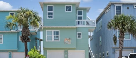 A multi-story building with a sign that reads 'Slick Paradise.' There are two garage doors, a staircase, and a white pickup truck parked in front.