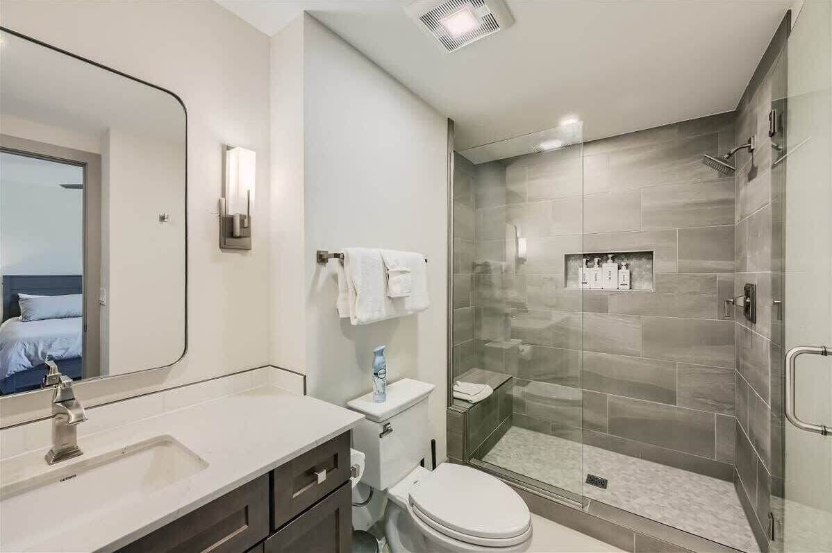 Une salle de bain moderne avec une douche à parois de verre, un grand miroir et des toilettes.
