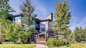 Une maison moderne à deux étages, dotée d’un porche abrité, entourée d’arbres et d’une pelouse bien entretenue.
