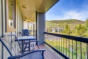 Un balcón con una mesa y sillas, con vistas a un área residencial con casas y árboles.