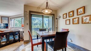 Un espace repas comprenant une table et des chaises, un lustre et des œuvres d’art encadrées accrochées au mur.