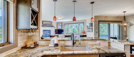 A modern kitchen with granite countertops, wooden cabinets, and pendant lighting.