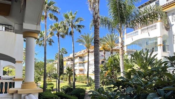 A hotel with a courtyard featuring palm trees and a well-maintained garden. - Modern 2-bedroom Apartment With Private Underground Parking Lift Access (Marbella)