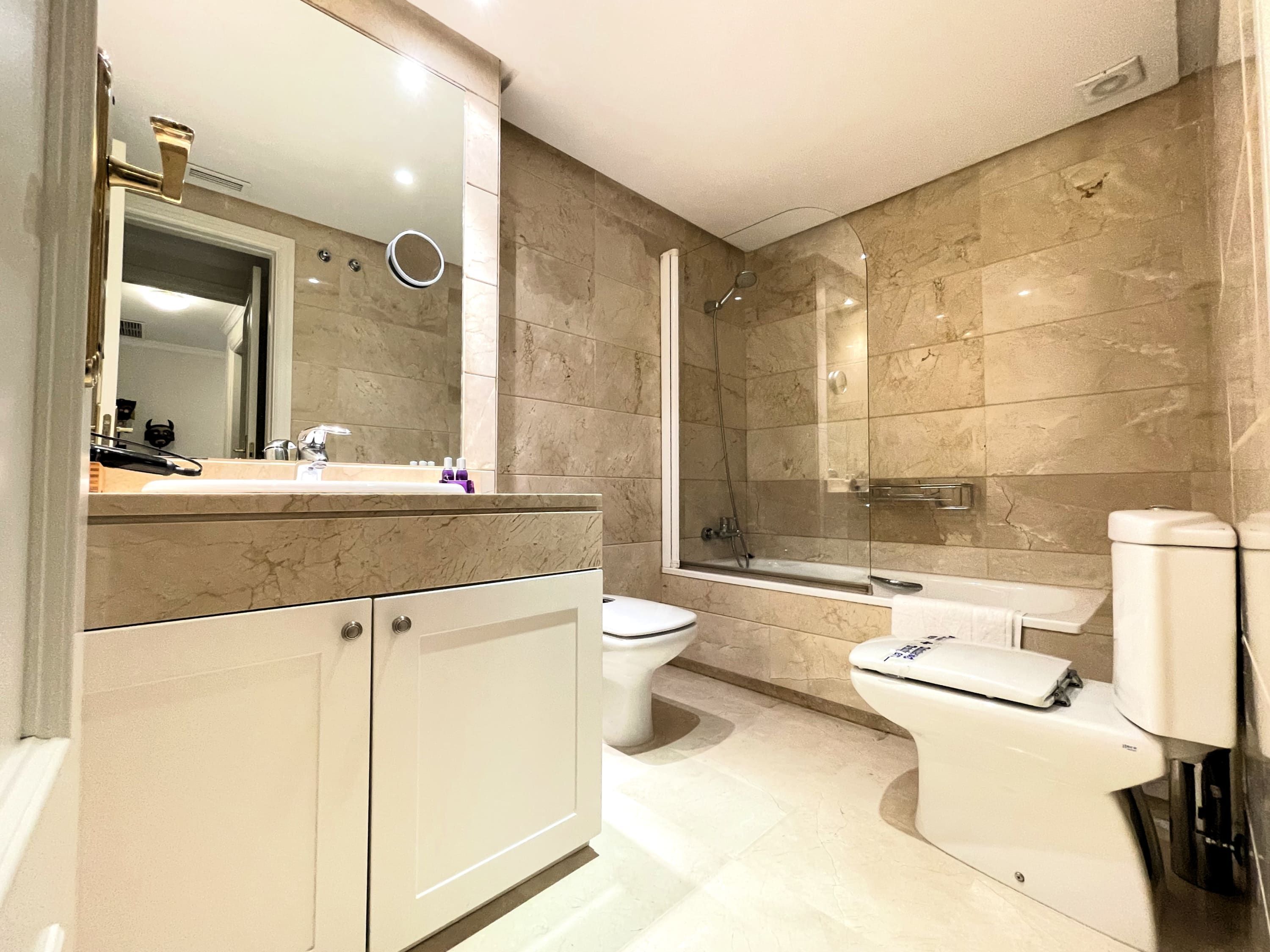 A modern bathroom with a shower, toilet, and sink.