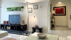 A living room with a flat-screen TV, a floor lamp, a decorative bowl, and a framed artwork on the wall. - Modern 2-bedroom Apartment With Private Underground Parking Lift Access (Marbella)