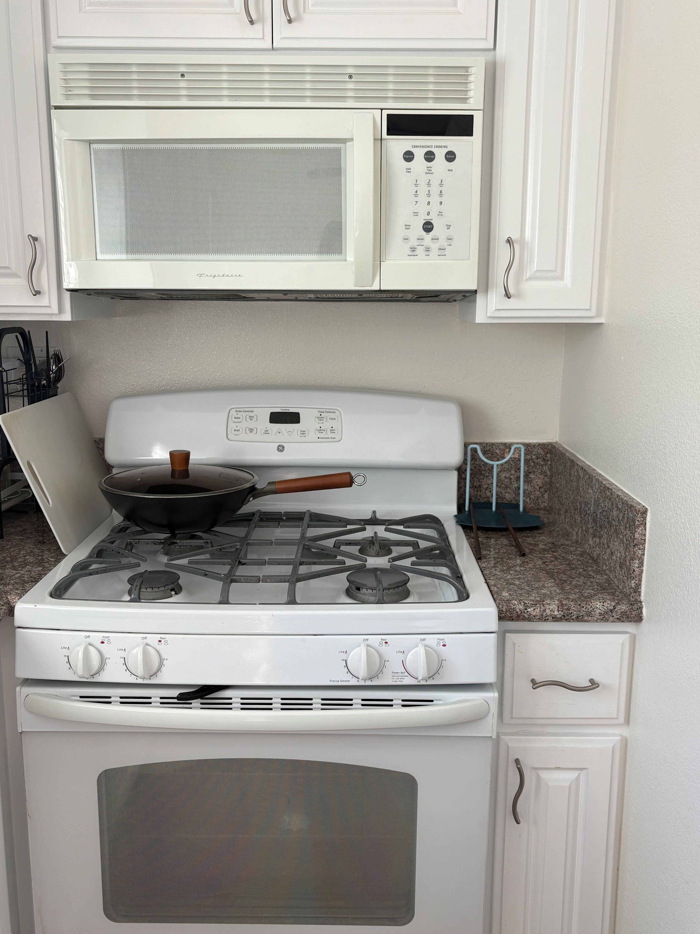 A kitchen with a gas stove, a microwave, and a stove top oven.