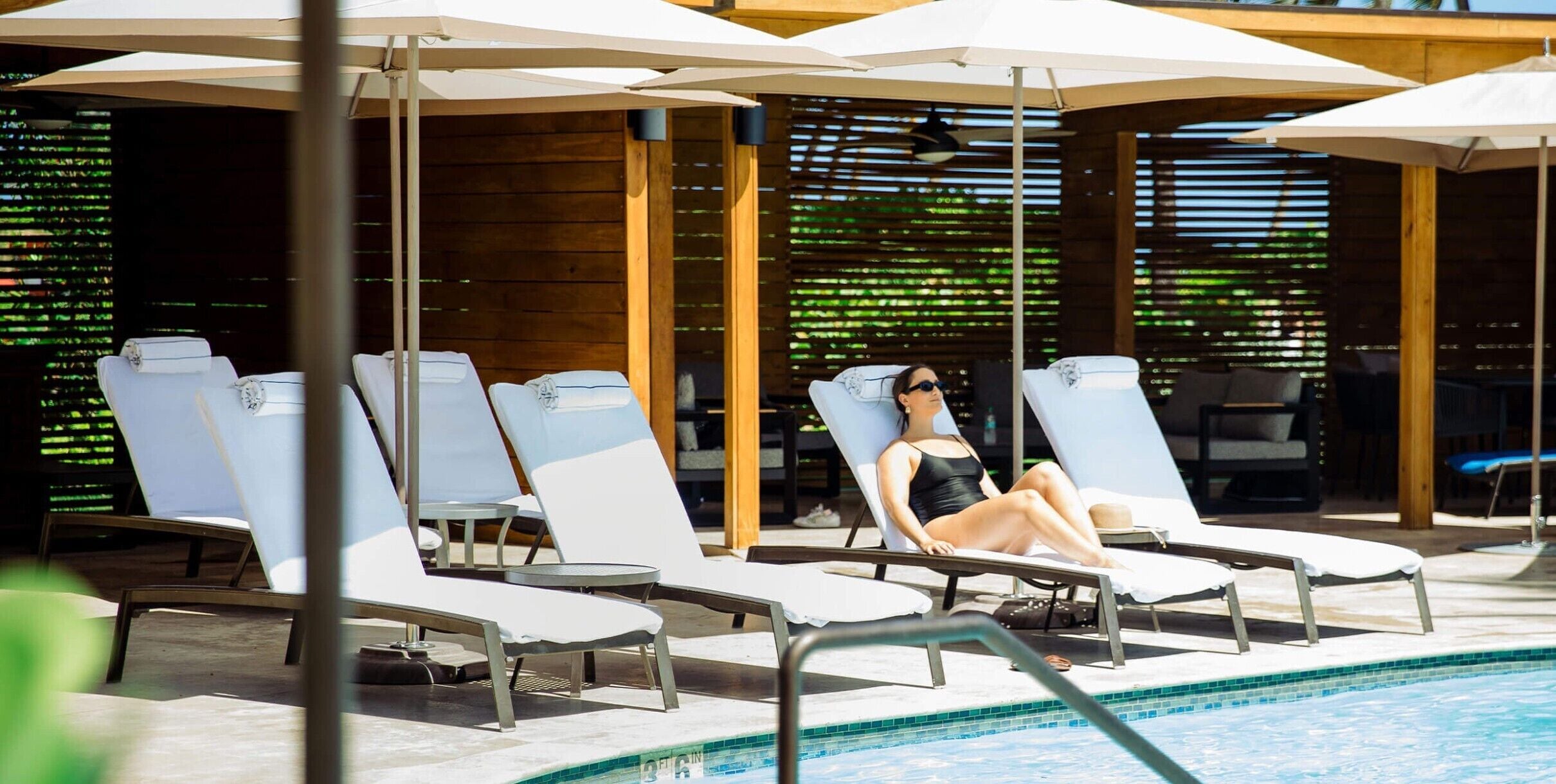 A poolside area with lounge chairs and umbrellas.