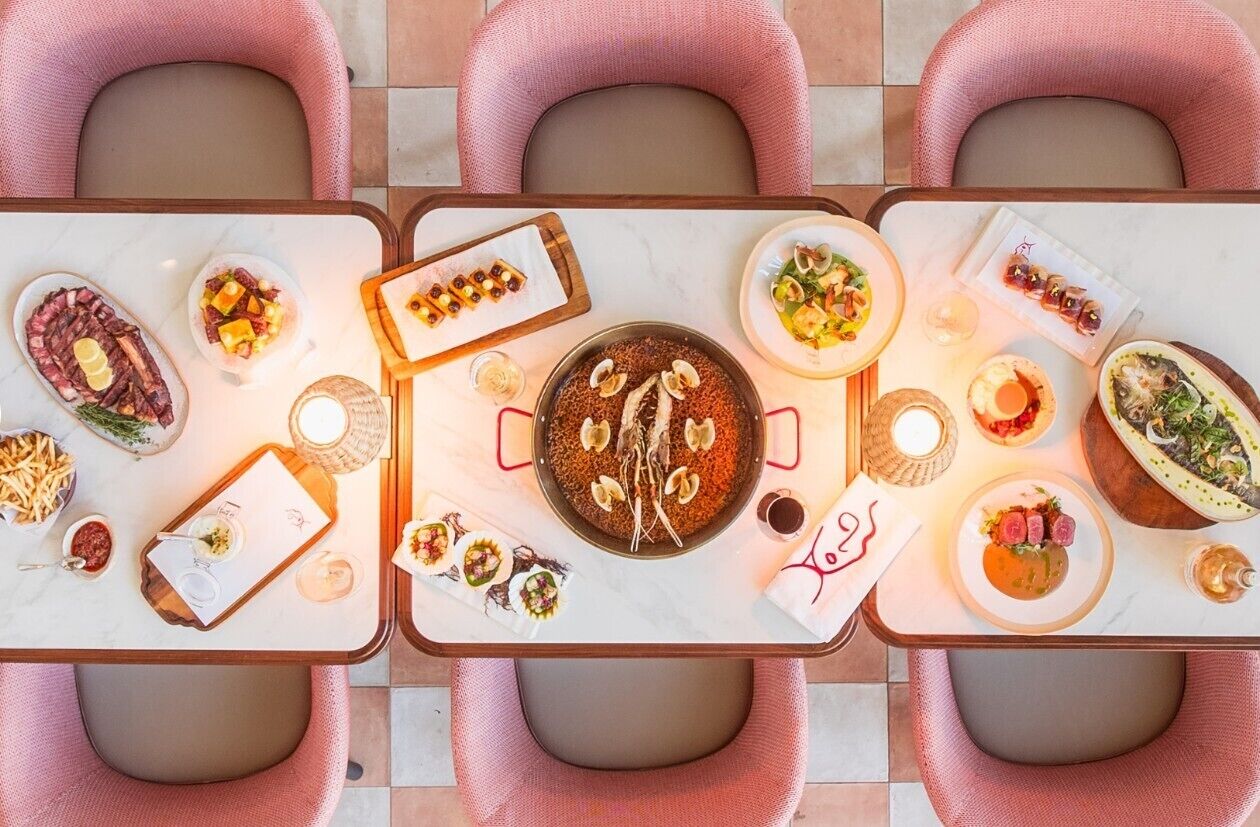 Una mesa de comedor con varios platos, incluyendo un tazón de arroz, una porción de sushi y un bol de sopa.
