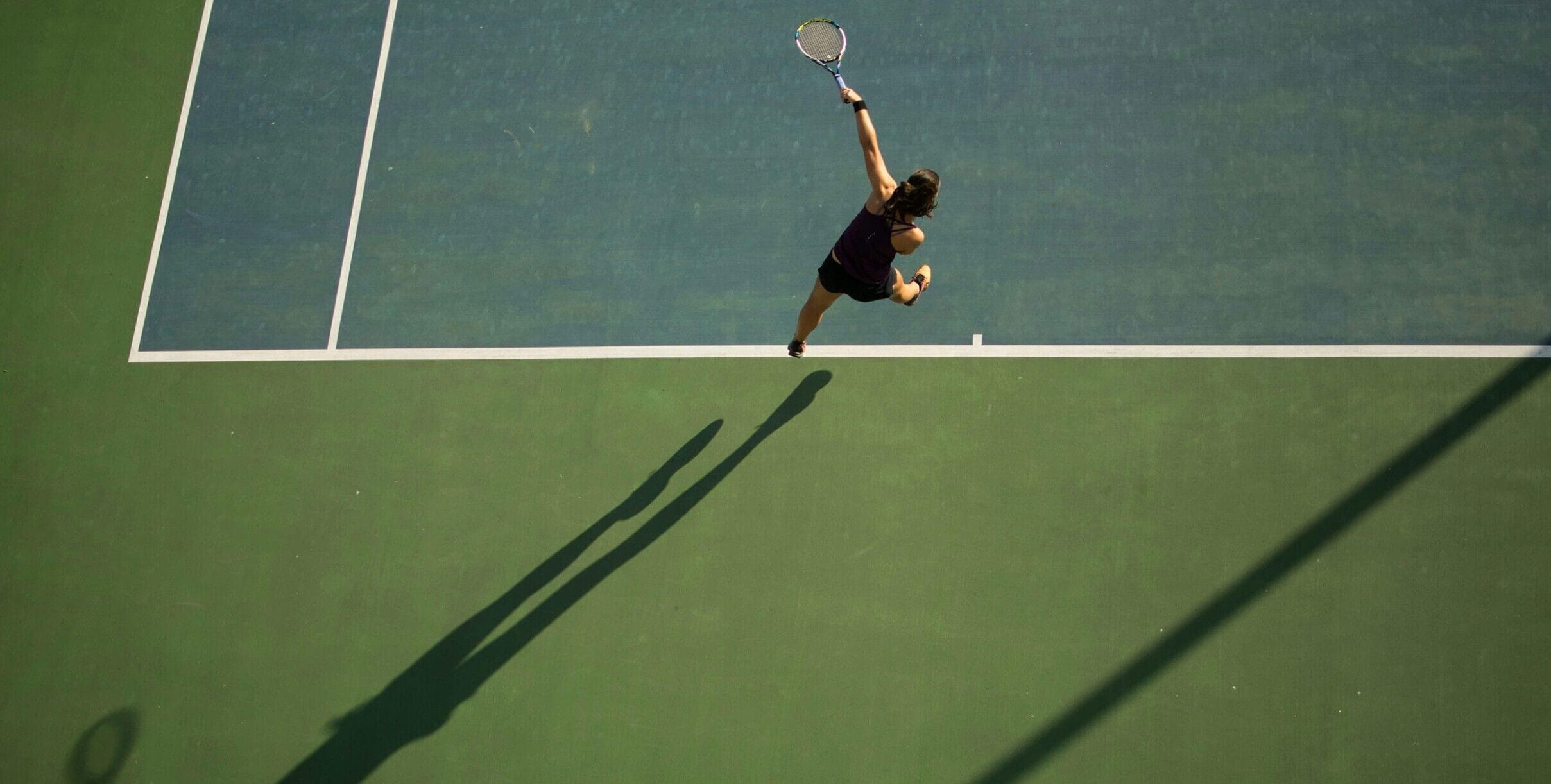 A tennis court with a player in mid-action.