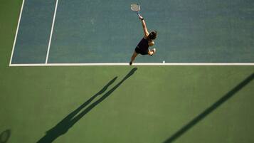 A tennis court with a player in mid-action.