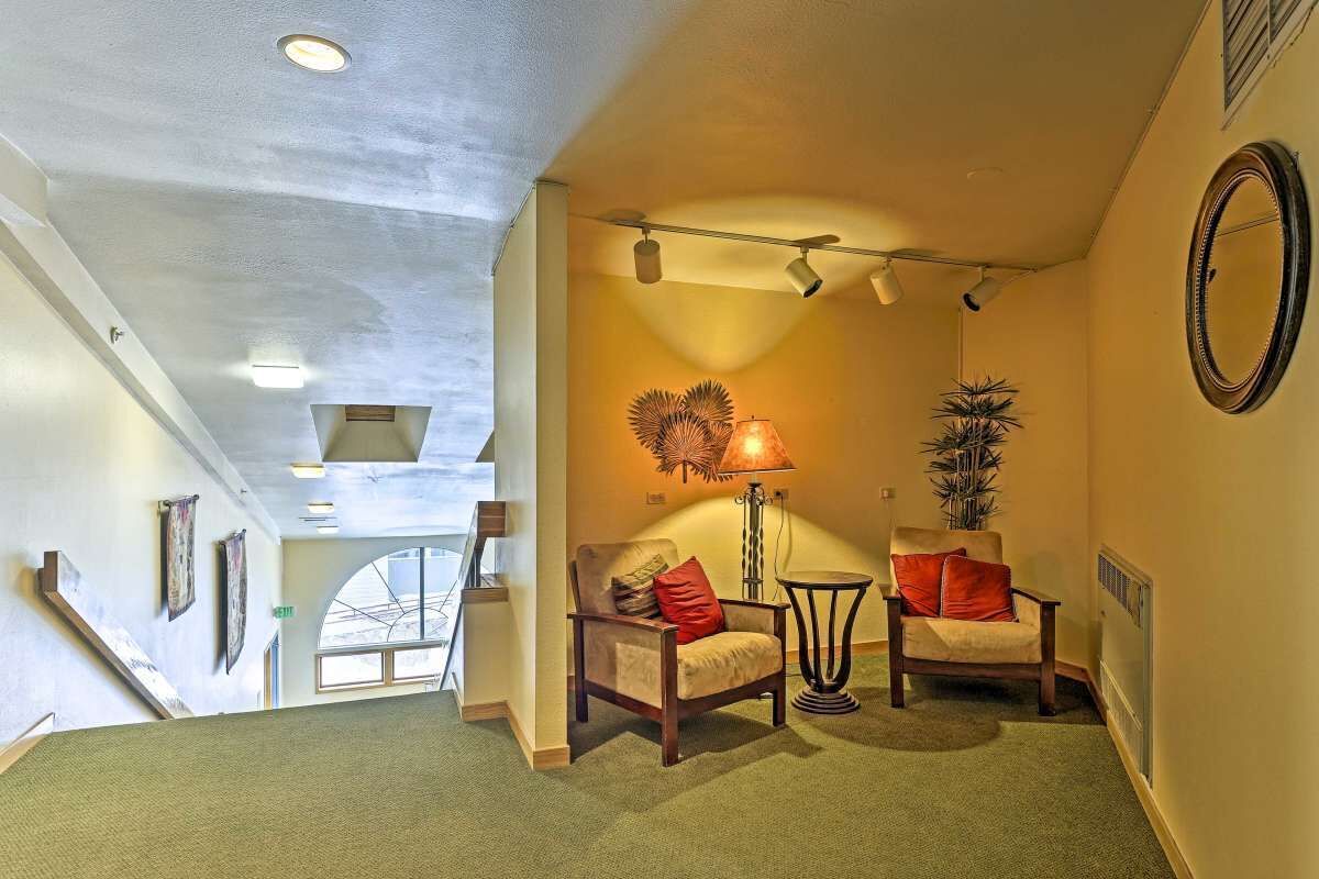 A hallway with two armchairs, a lamp, and a mirror on the wall.