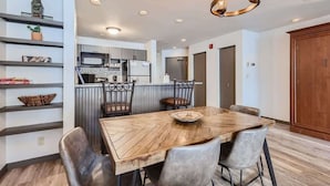 A modern kitchen with a microwave, refrigerator, and a dining area with a wooden table and chairs. - Near Lifts, Ski Keystone, Sleeps up to 6 People (Keystone)