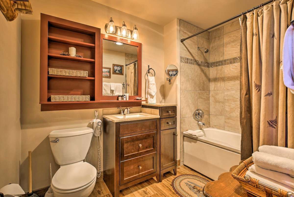 A bathroom with a toilet, sink, vanity, mirror, shower, and bathtub.