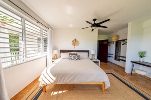 A bedroom with a bed, a ceiling fan, a nightstand, a bedside table, a wall-mounted shelf, and a window with blinds. - Villa Ventosa - Pool, King-Size Beds, Solar, ACs, Superhost & Guest Favorite (Rincón)