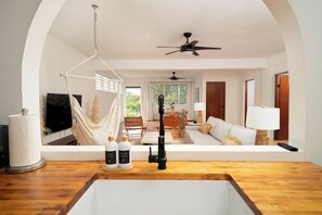 A modern living room with a wooden floor, a hanging chair, a sofa, a TV, and a ceiling fan. - Villa Ventosa - Pool, King-Size Beds, Solar, ACs, Superhost & Guest Favorite (Rincón)