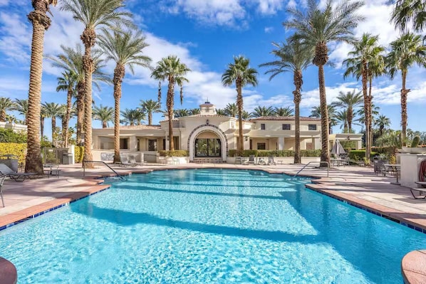 A swimming pool surrounded by palm trees and a building with a central archway. - Desert Dream | Pool, Spa, Gym, Near Golf (La Quinta)