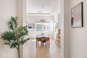 A dining area with a table, chairs, a hanging light fixture, and a potted plant. - Desert Dream | Pool, Spa, Gym, Near Golf (La Quinta)
