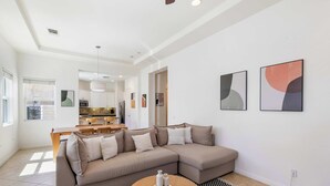 En moderne stue med en hjørnesofa, et spiseområde og kunst på væggene.