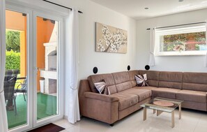 Un salon avec un canapé d’angle marron, une table basse en verre et un tableau accroché au mur.