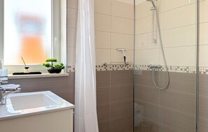 Une salle de bain moderne dotée d’une douche à parois de verre, d’un lavabo et d’une fenêtre offrant une vue agréable.